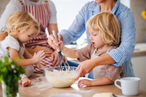 Midsection of young family with two small children indoors in kitchen, cooking.
